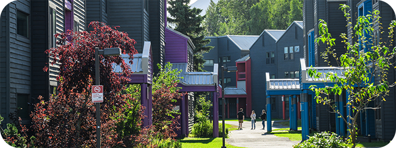 Outside image of residence halls with a group of students on the sidewalk